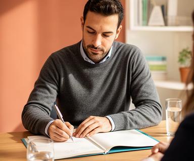 Asesor financiero tomando notas durante una reunión de planificación económica en Andalucía